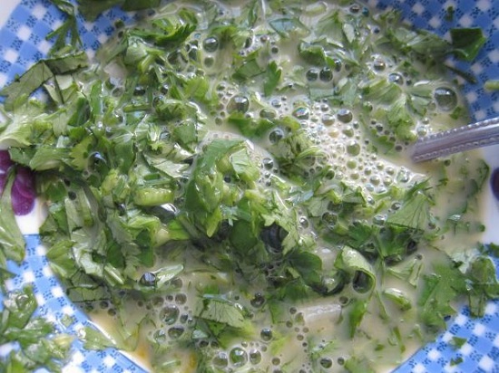 Добавим в яичную смесь рубленую зелень и чесночный зубчик